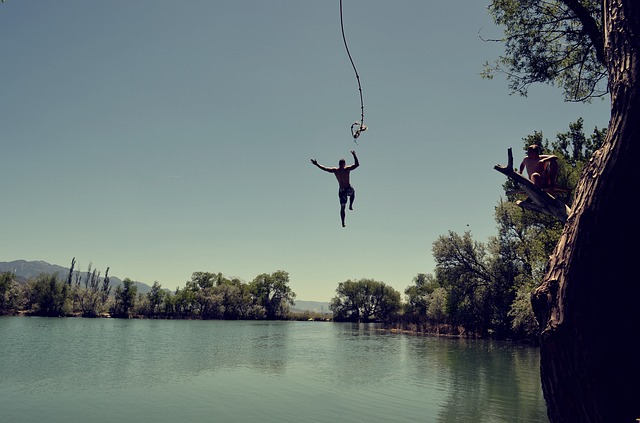 man jumping in lake